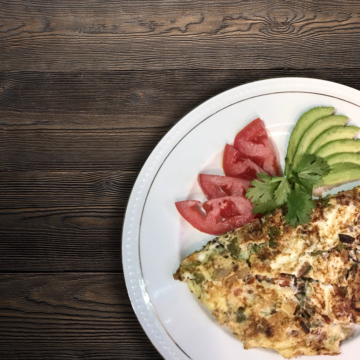 Machacado omelette served with sliced tomato, avocado and cilantro
